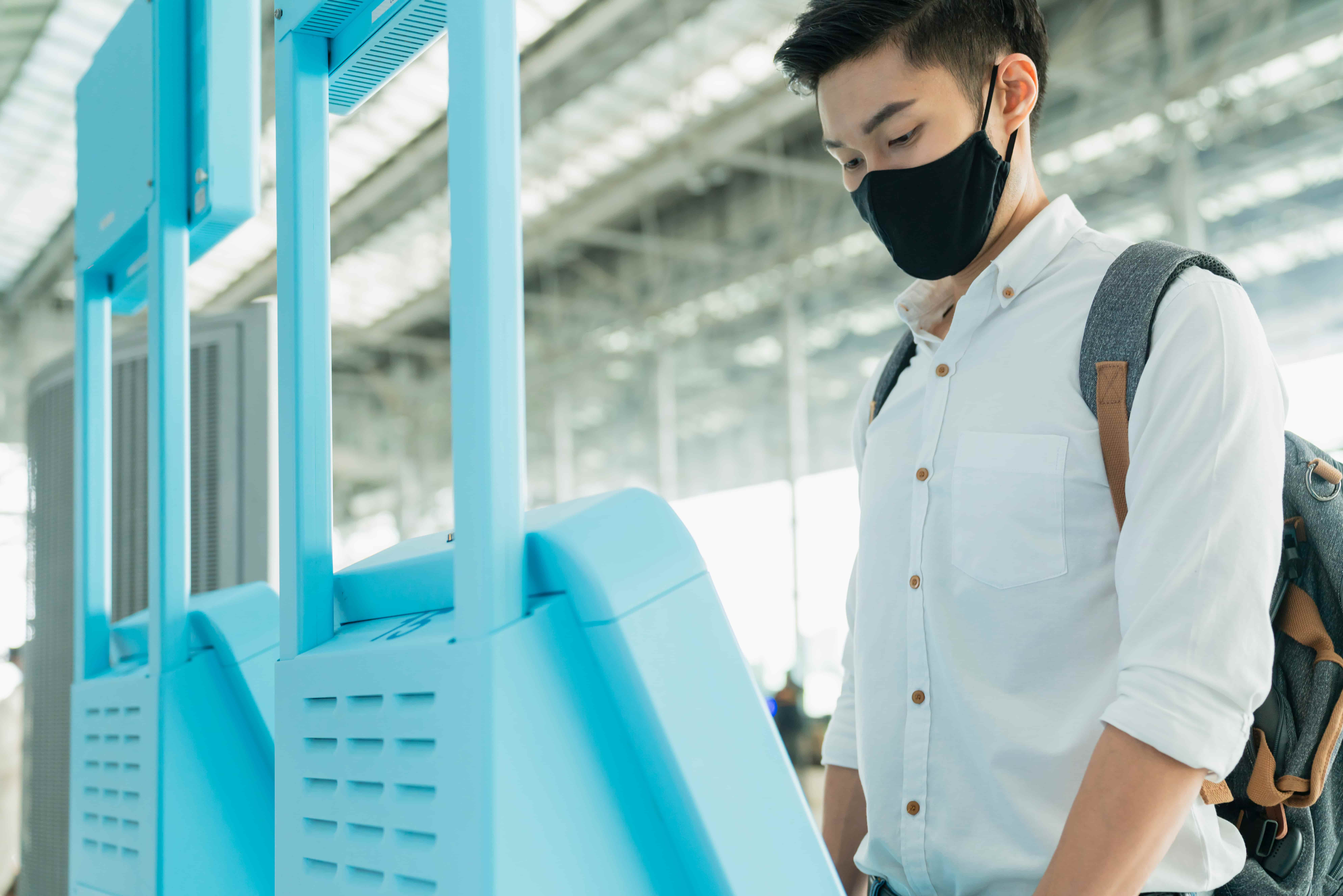 A man using interactive kiosk for his activities in a public area